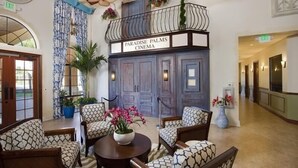 A lobby with a sign reading "Paradise Palms Cinema," featuring a balcony with plants, patterned chairs, and ceiling fans. - Ov3235 - Paradise Palms - 4 Bed 3 Baths Townhome (Kissimmee)