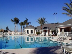 A swimming pool with lounge chairs and palm trees, surrounded by buildings with a classic architectural style. - Ov2570 - Windsor Palms Resort - 4 Bed 3 Baths Townhome (Kissimmee)
