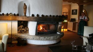 A stone fireplace with a fire, a statue, and a wooden shelf with pinecones. - Hotel Schloss Berg (Berg)