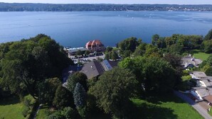An aerial view of a lakeside property with a large building, green lawns, and a clear view of the lake. - Hotel Schloss Berg (Berg)
