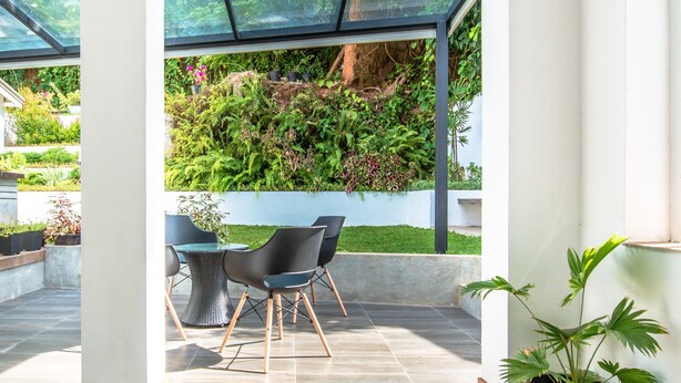 Un intérieur moderne avec un plafond en verre, un coin repas avec des chaises et une plante en pot.