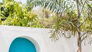 Un bâtiment blanc avec une porte bleue et un arbre devant.