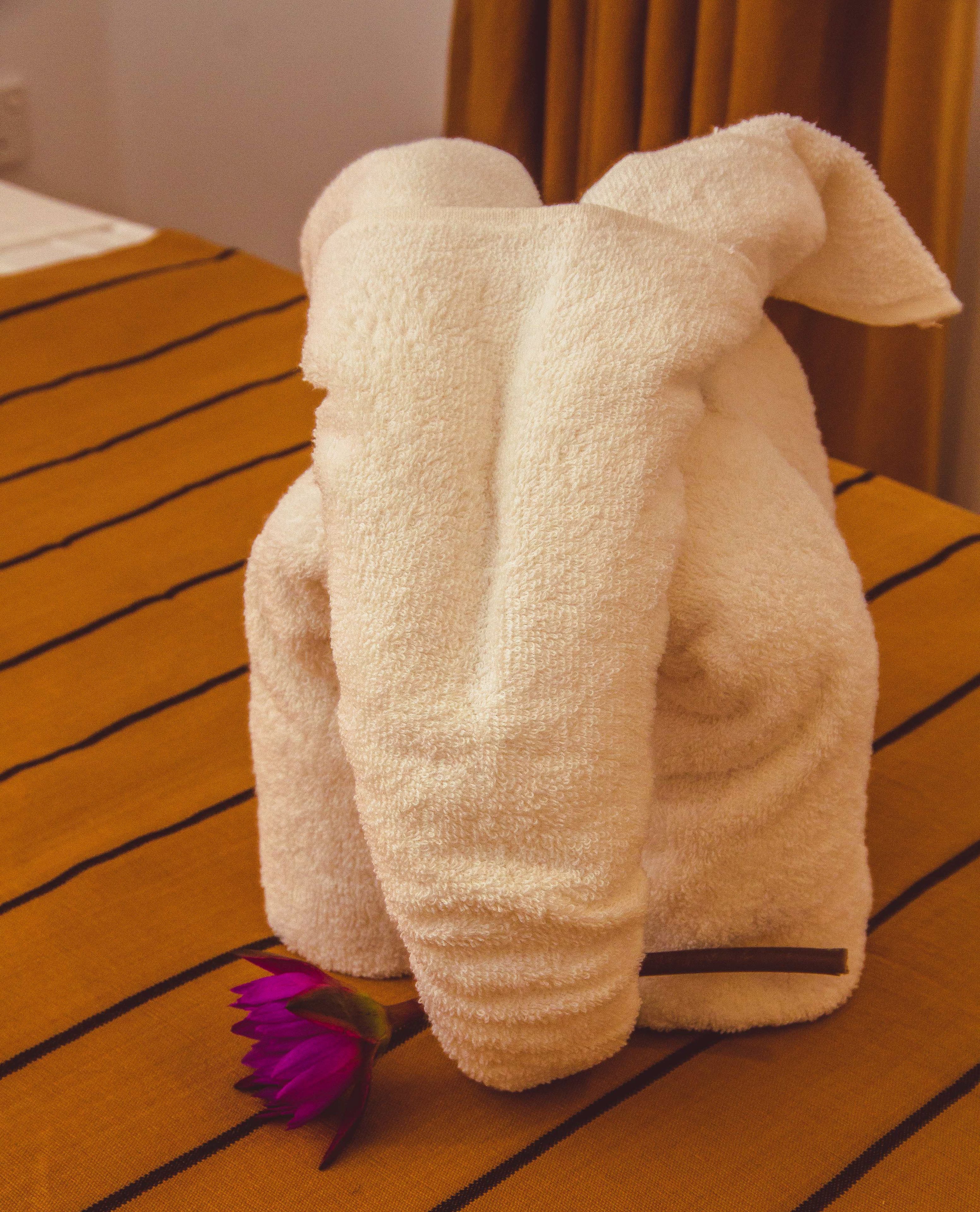 A plush toy resembling a rabbit on a striped fabric surface.