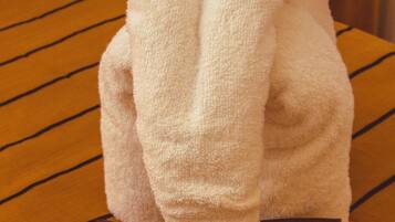 A plush toy resembling a rabbit on a striped fabric surface.