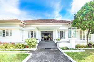 A two-story house with a tiled roof, a front porch, and a statue in the garden.