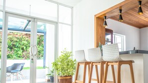 Une cuisine moderne avec des tabourets en bois, une plante en pot et une grande fenêtre.
