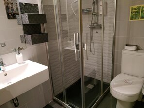 A modern bathroom with a glass-enclosed shower, a white sink, and a toilet. - Hotel Ginebra (Barcelona)