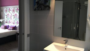 A modern bathroom with a shower, a sink, and a mirror. - Hotel Ginebra (Barcelona)