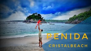 A beach scene with a man lifting a child, boats in the water, and text 'PENIDA CRISTALBEACH'. - Toro Cottage (Penida Island)