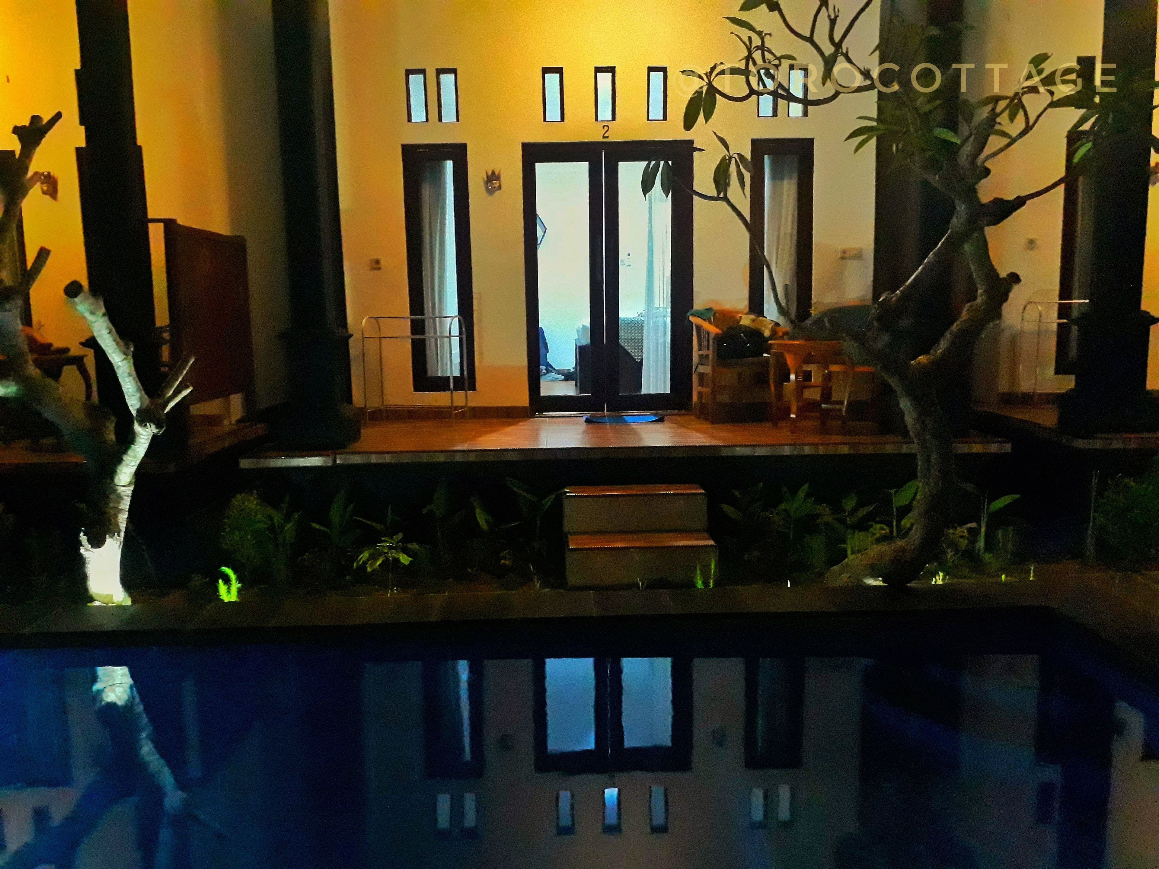 A modern building with a reflective pool in front, a wooden deck, and a sign reading "COTTAGE".