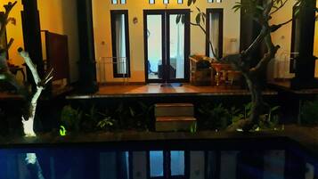 A modern building with a reflective pool in front, a wooden deck, and a sign reading "COTTAGE".