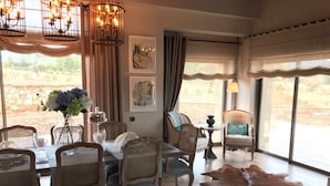 A dining area with wicker chairs, a dining table, and a large leather rug. - Regnum Golf Country 3 bedroom (Bodrum)