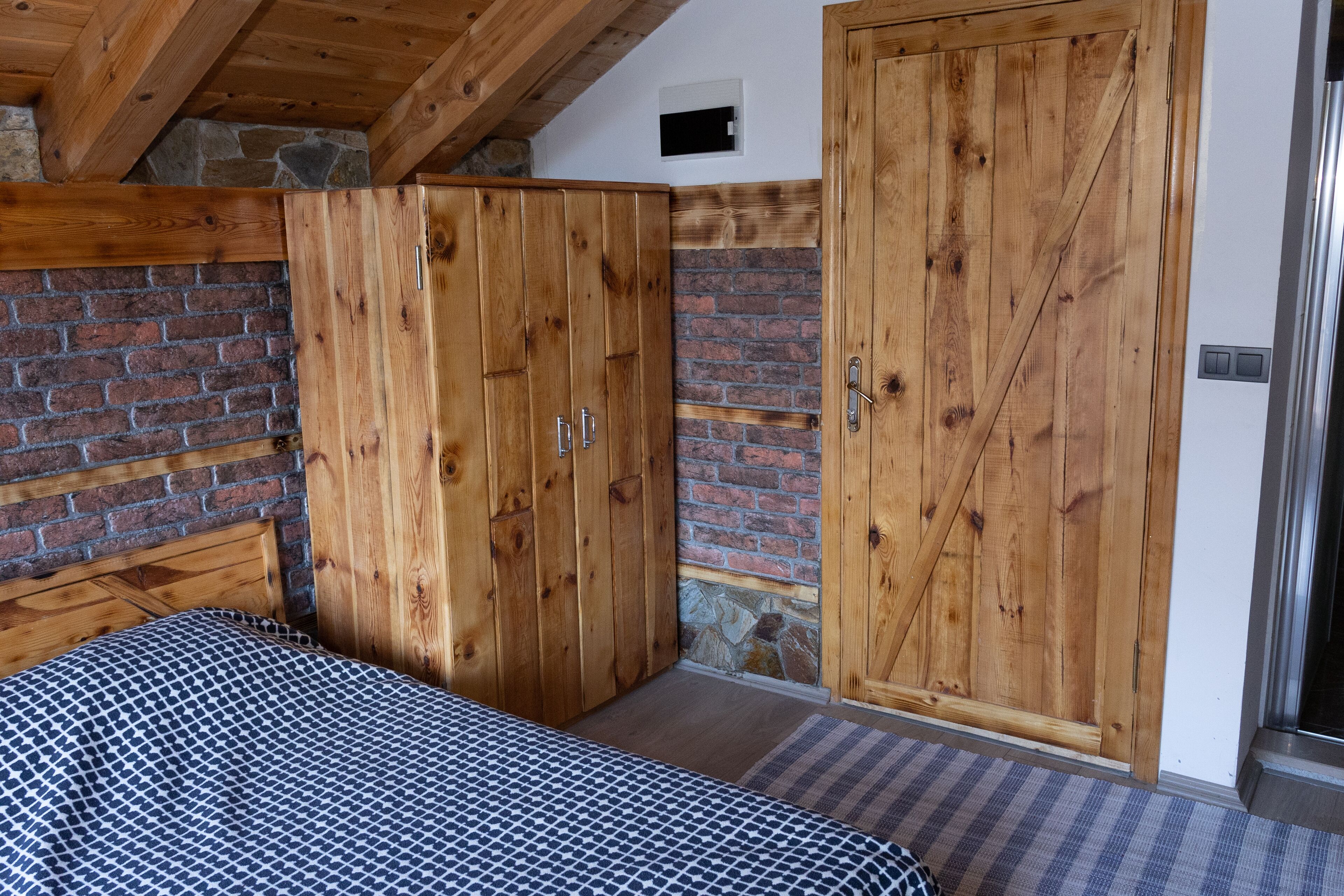 Un dormitorio con cama, armario de madera, pared de ladrillo y detalles de piedra.