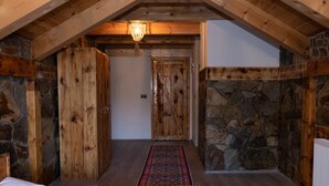 Techo de madera, una cama, pared de piedra y una puerta.