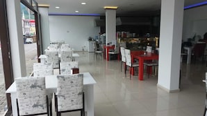 Un restaurante con mesas blancas y rojas, sillas estampadas y piso de baldosas.