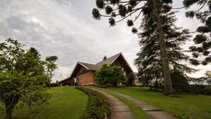 A rustic wooden house with a stone pathway leading to the entrance. - Pousada Déjà Vu (Campos do Jordão)