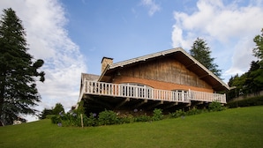 A wooden chalet with a balcony, surrounded by greenery and trees. - Pousada Déjà Vu (Campos do Jordão)