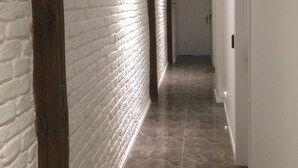 A hallway with white brick walls, dark wooden beams, and a shiny tiled floor. - Studio Rental Central Warsaw (Warsaw)