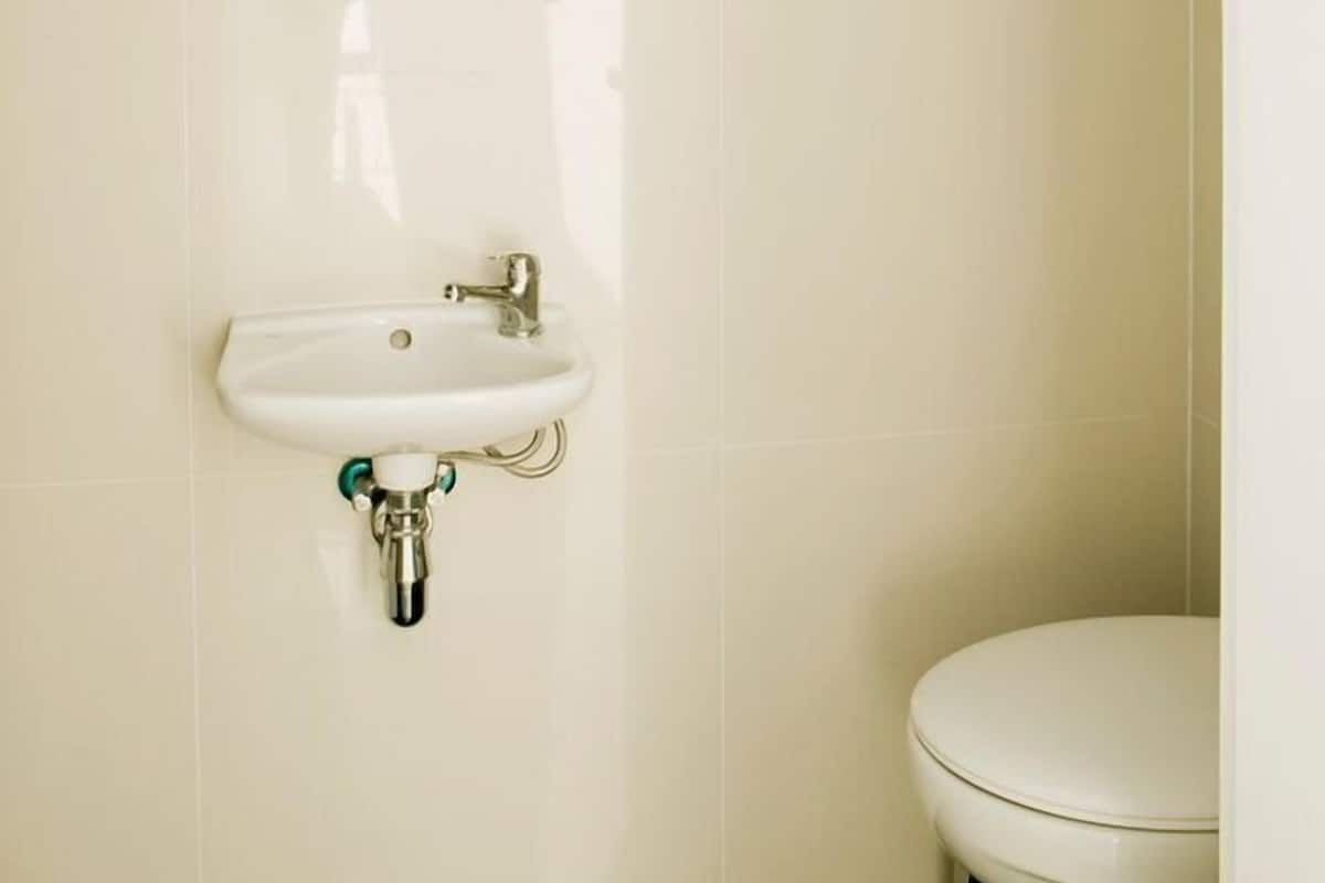 A bathroom with a round mirror, a sink, and a toilet.
