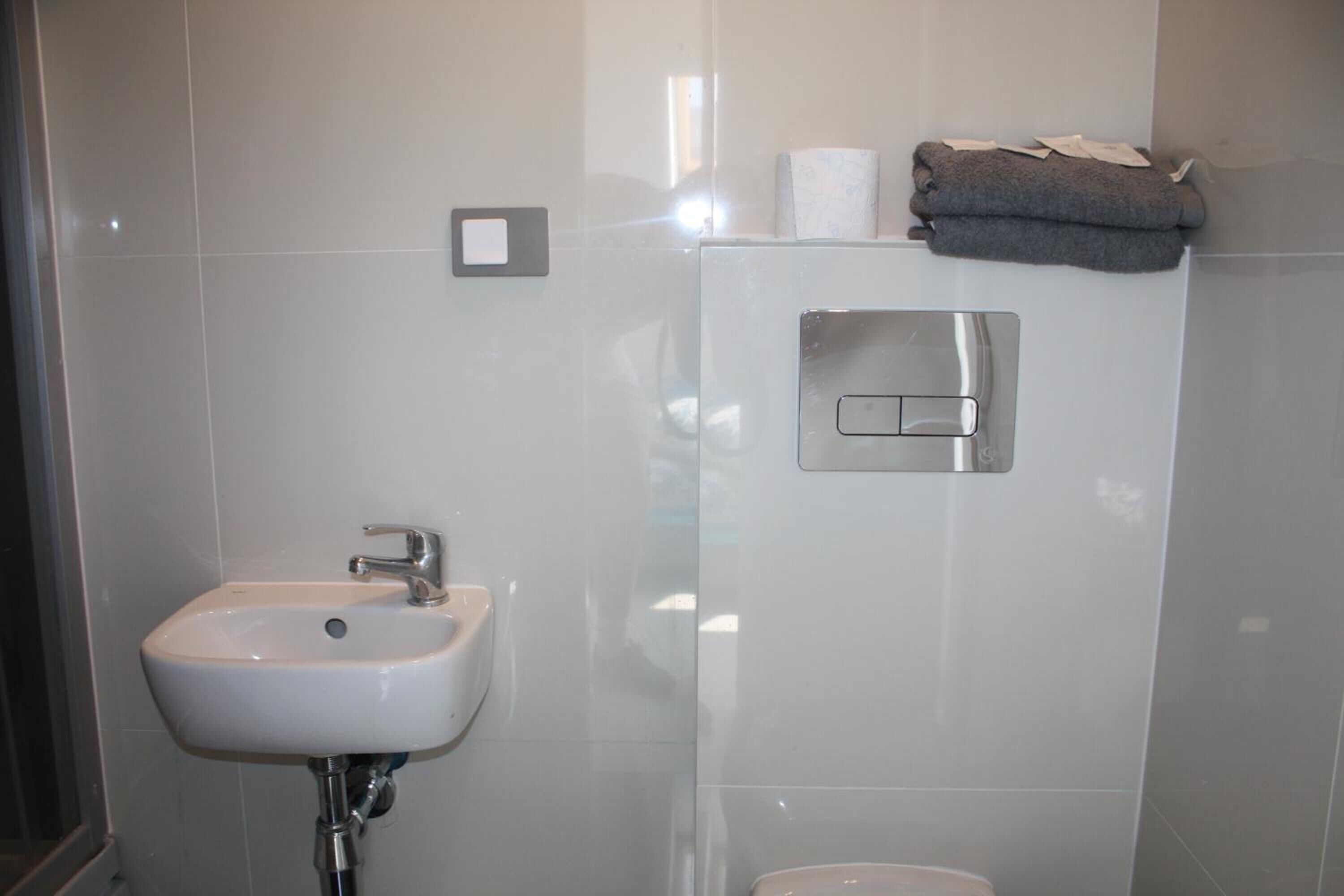 A bathroom with a white sink, a towel dispenser, and a toilet.