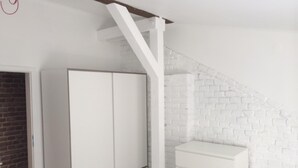 A room with a white wardrobe, a white dresser, and a brick wall. - Studio Rental Central Warsaw (Warsaw)