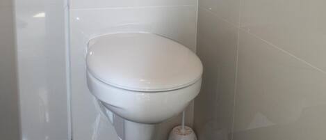 A modern bathroom with a white toilet, a flush handle, and a toilet paper holder.