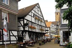 A traditional half-timbered building with outdoor seating and a signboard. - Zur alten Krone (Hattingen)