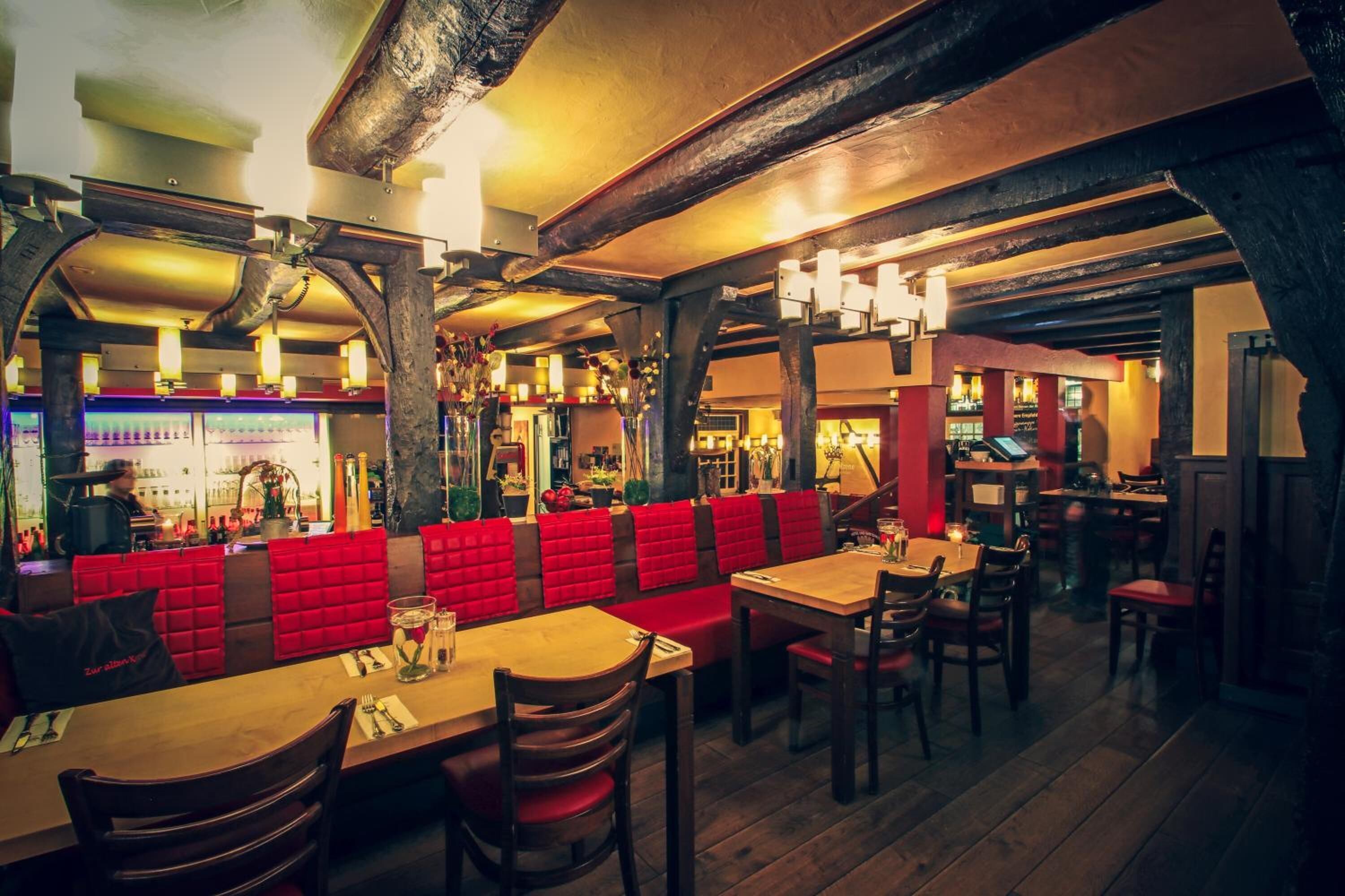 A restaurant with wooden tables and red cushioned booths.