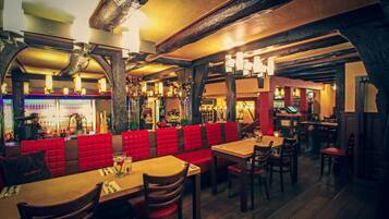 A restaurant with wooden tables and red cushioned booths.
