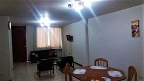 Un comedor con una mesa y sillas, un sofá y un televisor instalado en la pared.