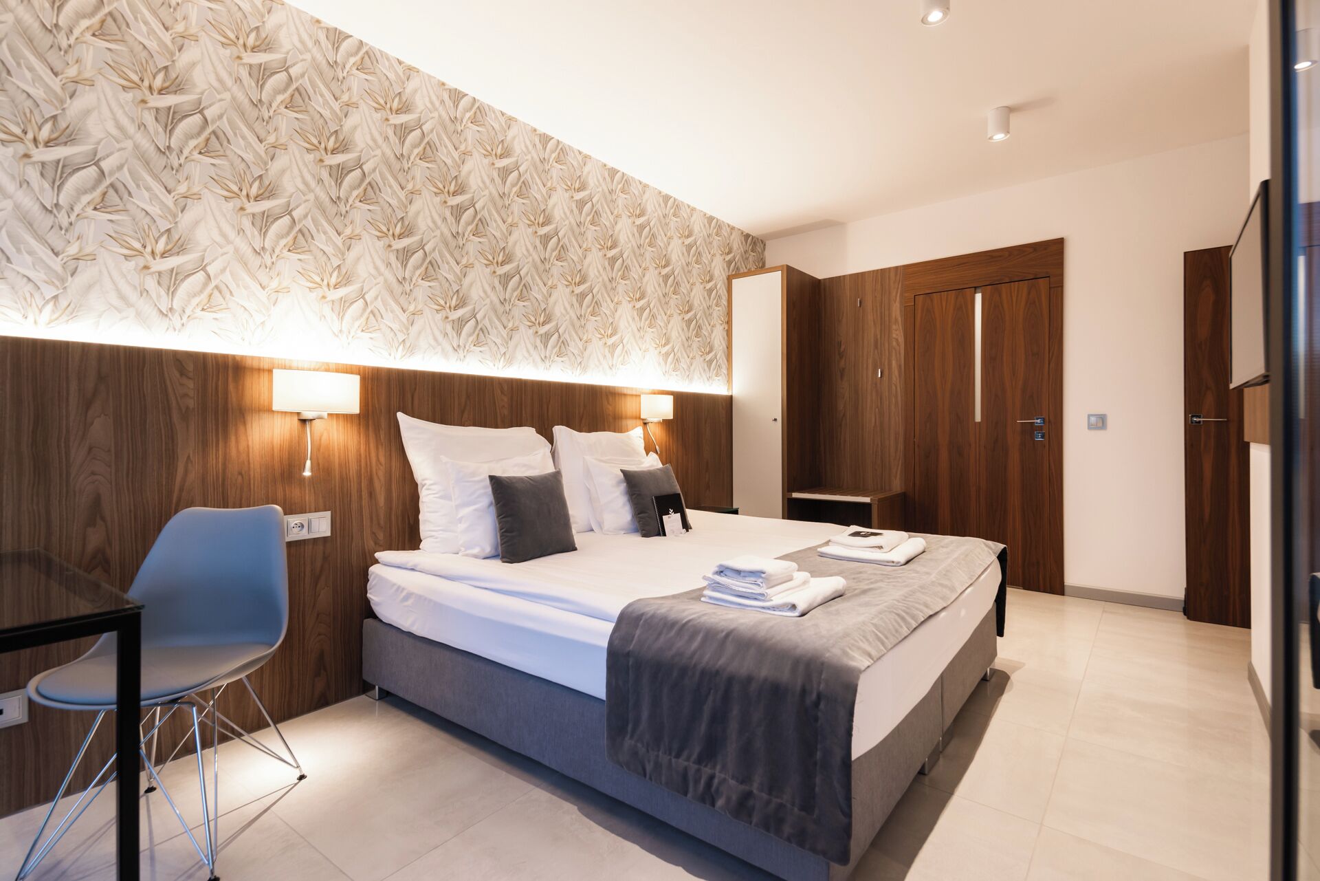 Een moderne hotelkamer met een groot bed, een bureau en een kledingkast.