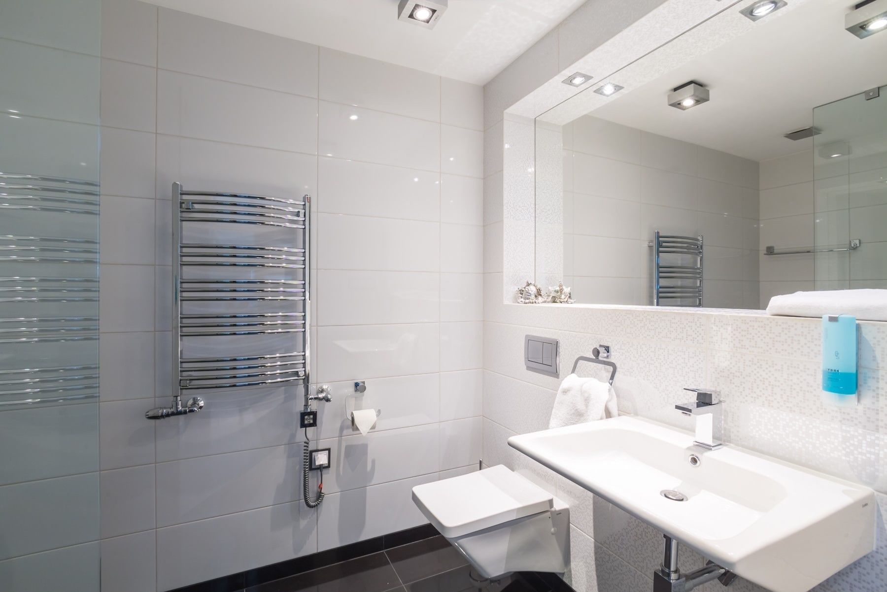 Un bany modern amb plat de dutxa de vidre, un lavabo blanc i un mirall gran.