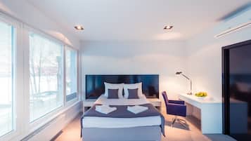 Un dormitorio moderno con una cama grande, un escritorio con silla y una ventana con persianas.