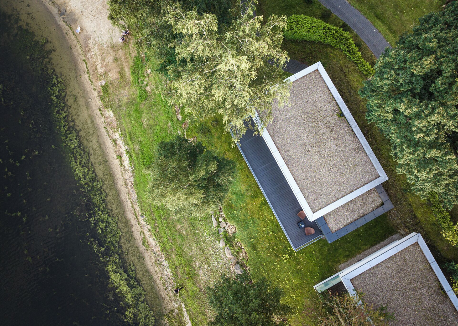 An aerial view of a property with a large open deck area, a small building with a sloped roof, and a pathway leading to the deck.