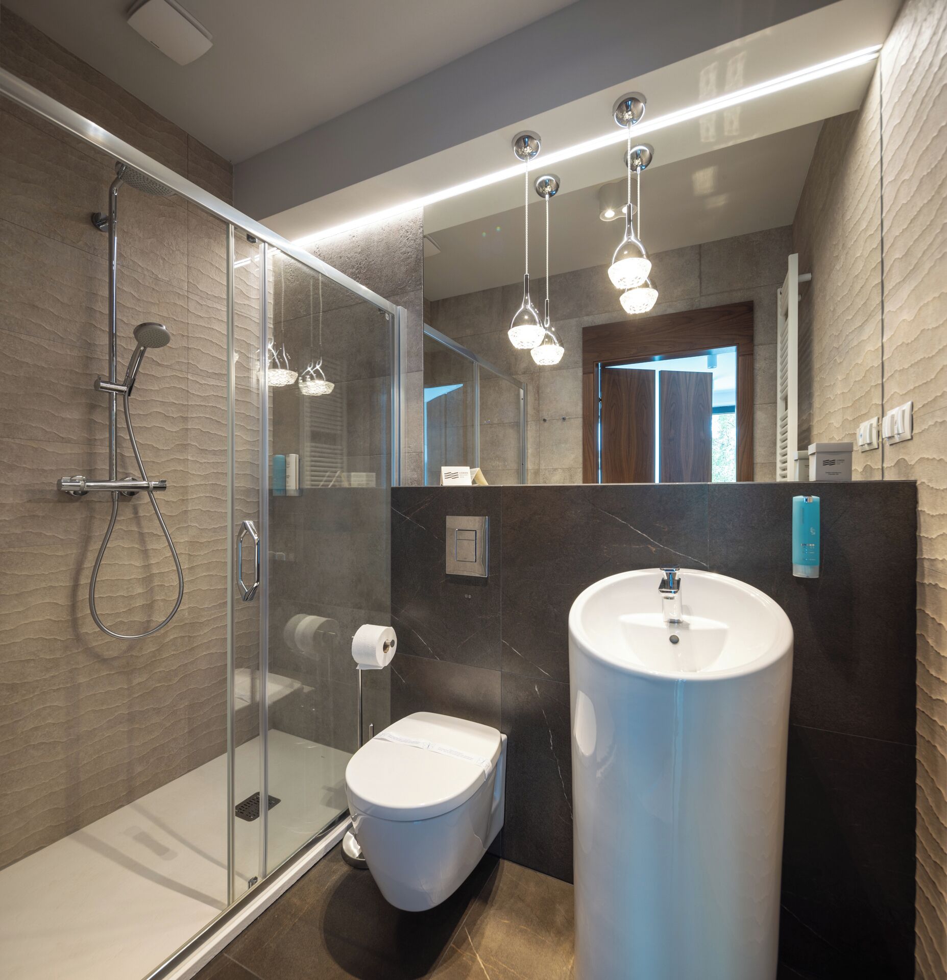 Une salle de bain moderne avec une douche à parois de verre, des toilettes et un grand lavabo.