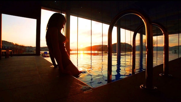 A person by a pool with a view of the sunset over water and hills. - Lemon Resort Spa (Grodek Nad Dunajcem)