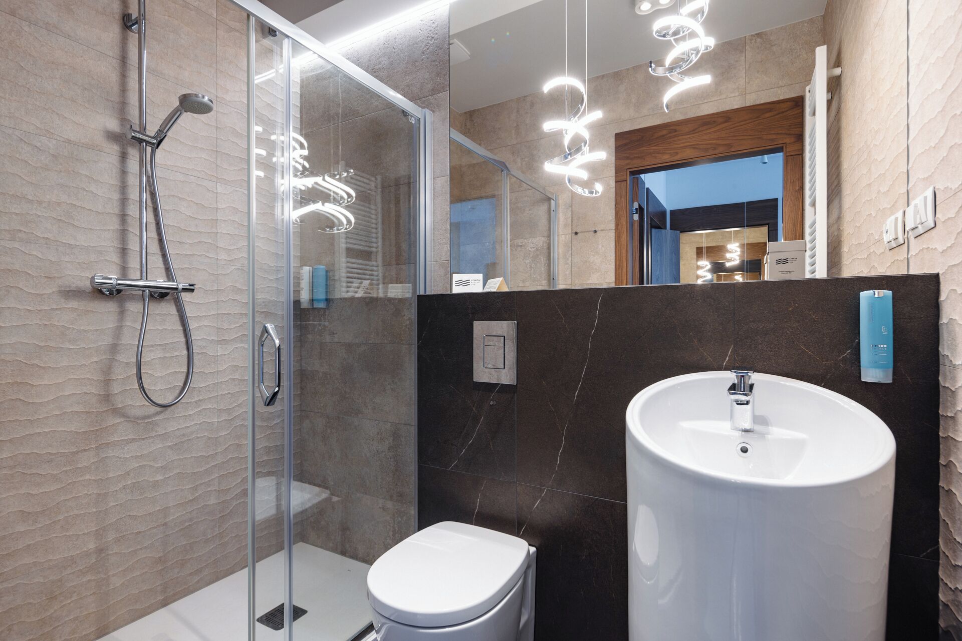 A modern bathroom with a glass-enclosed shower, a white toilet, and a large sink.