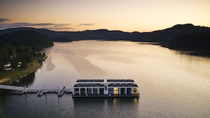 A modern floating houseboat with a dock on a calm lake, surrounded by hills. - Lemon Resort Spa (Grodek Nad Dunajcem)