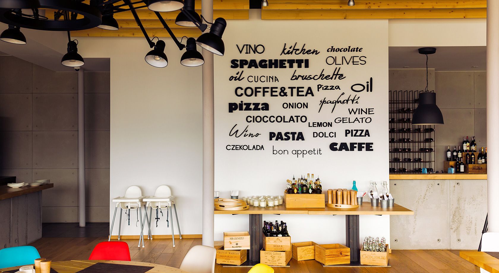 Une cuisine moderne avec un nuage de mots sur le mur, dans lequel figurent des noms d’aliments comme les spaghettis, la pizza et le vin.