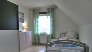 Ein Schlafzimmer mit Bett, Kommode, Heizkörper und einem fenster mit Vorhängen.