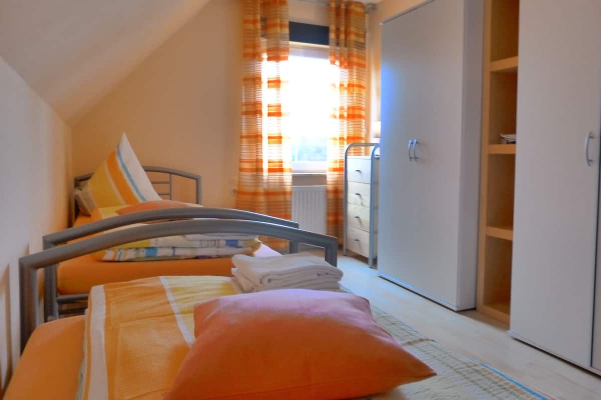 Un dormitorio con cama, armario y ventana con cortinas.
