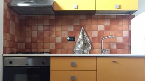 Uma cozinha com fogão, forno, armários amarelos e um tapete vermelho.
