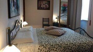 Quarto com cama, cadeira, escrivaninha e espelho.