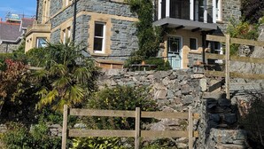 Une maison en pierre dotée d’un grand porche et d’un escalier en pierre à marches abruptes menant à l’entrée.