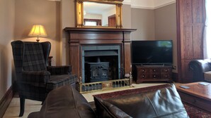 Un salon avec une cheminée, un téléviseur et un grand meuble en bois.