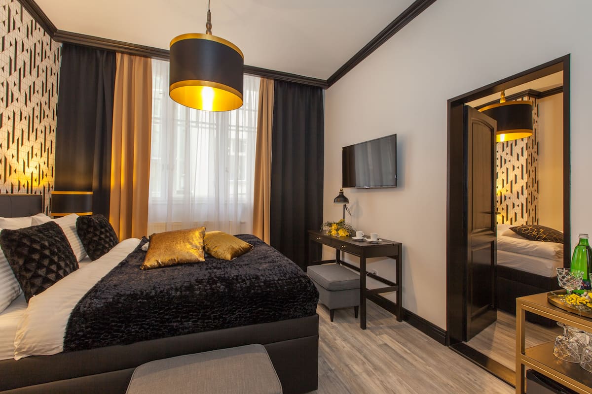 Moderni hotellihuone, jossa on suuri sänky, työpöytä, taulutelevisio ja peili.