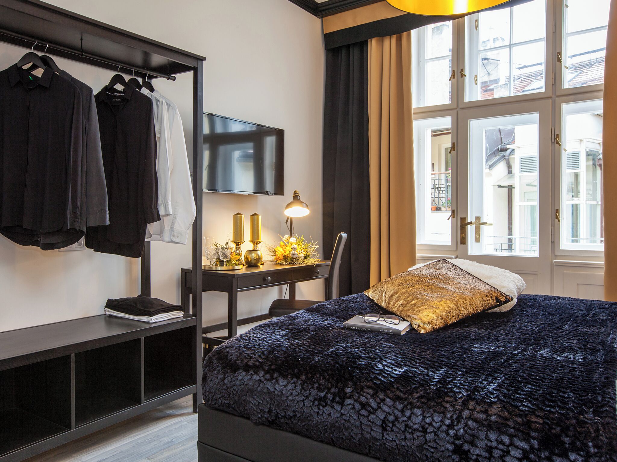 Une chambre à coucher avec un lit, un bureau avec une lampe, une télévision et une armoire.