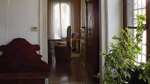 Un pasillo con un banco de madera, una planta en maceta y una puerta que da a otra habitación.