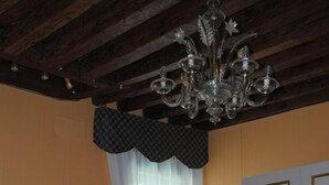Un dormitorio con cama, candelabro, ventana con cortinas y armario.