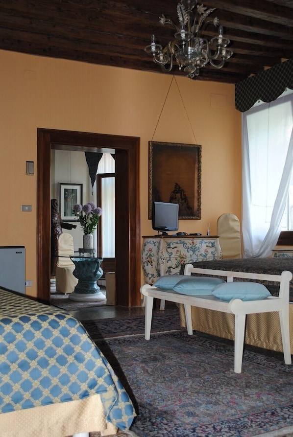 A room with a bed, a television, a painting, and a chandelier. - B&B San Firmino (Venice)